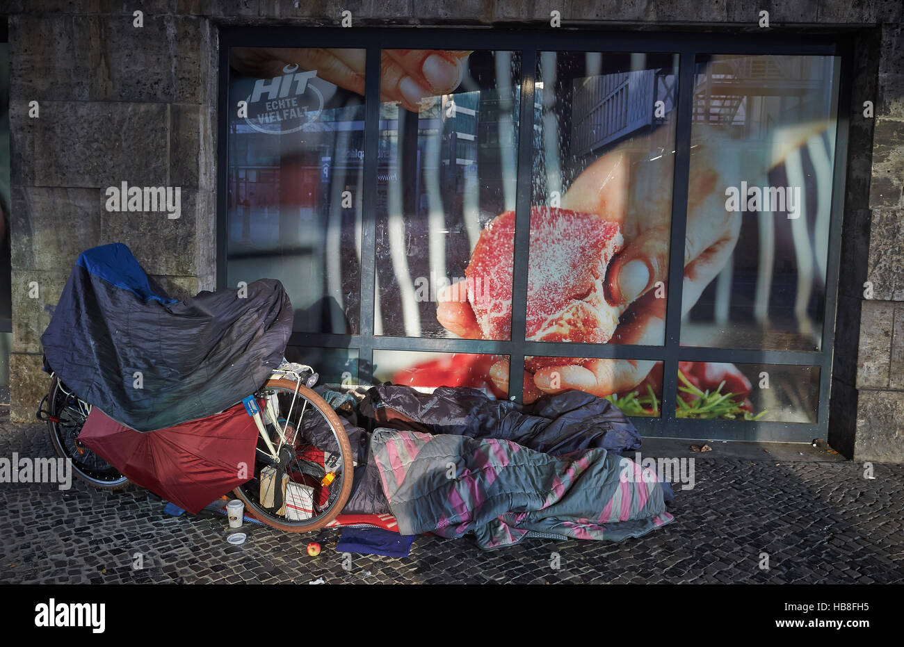 Homeless person sleeping on path in front of grocery store, Berlin, Germany Stock Photo