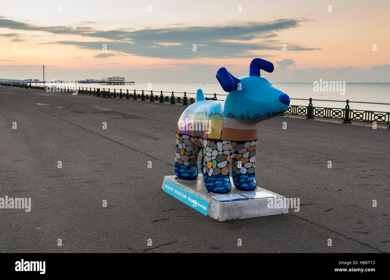 View of a Snowdog sculpture on Hove promenade at sunrise. The Snowdogs by the Sea public exhibition took place in 2016 to raise money for The Martlets Stock Photo