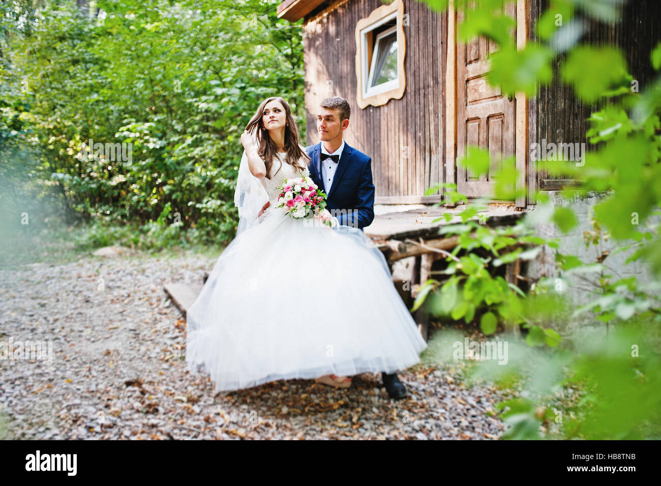 Wedding couple sitting near old wooden house Stock Photo