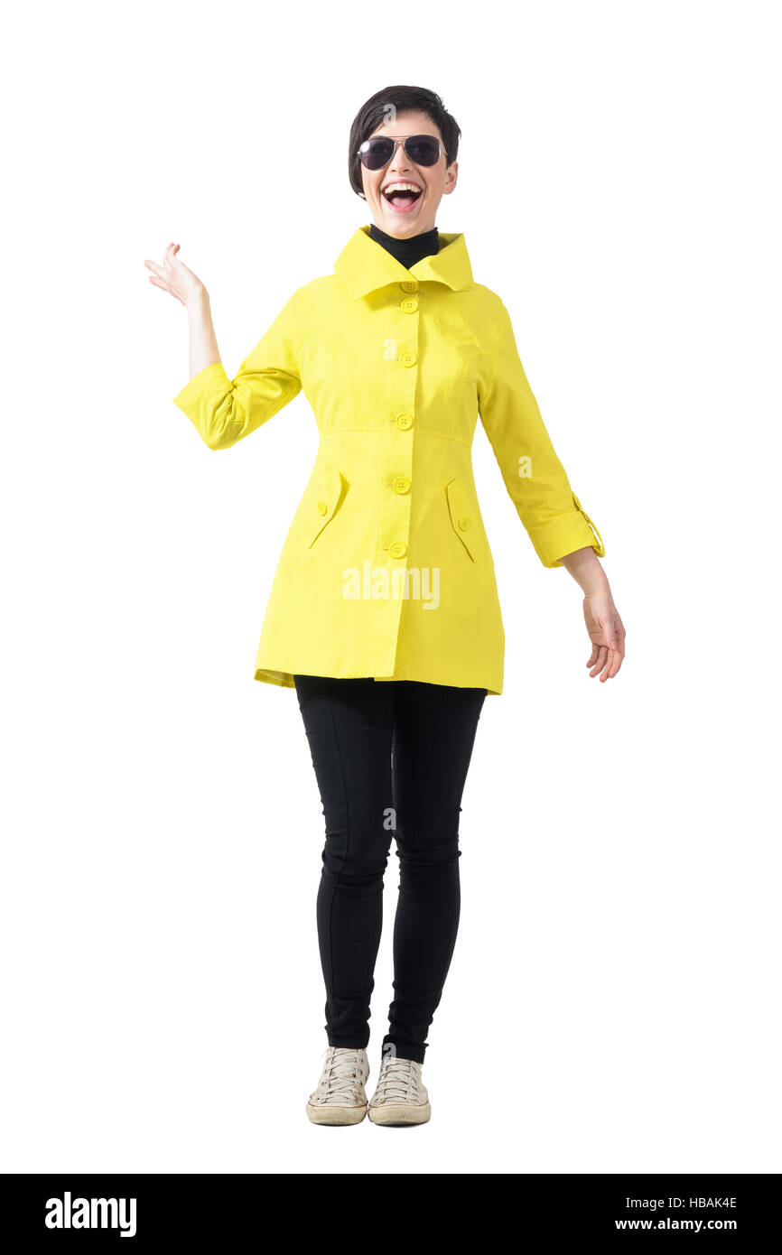 Excited young trendy woman in yellow raincoat. Full body length portrait isolated over white studio background. Stock Photo
