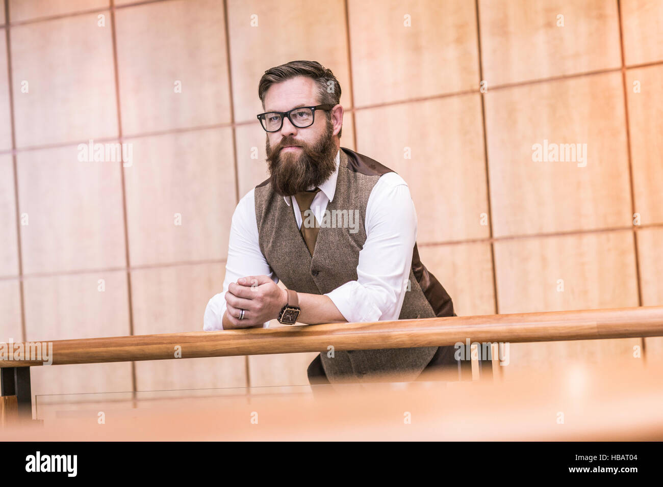 Businessman wearing tweed waistcoat looking out from  office balcony Stock Photo