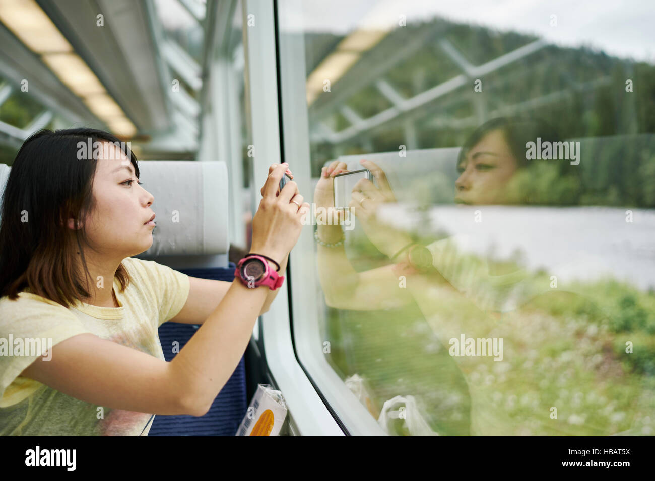 Female tourist photographing through passenger train window, Chur, Switzerland Stock Photo
