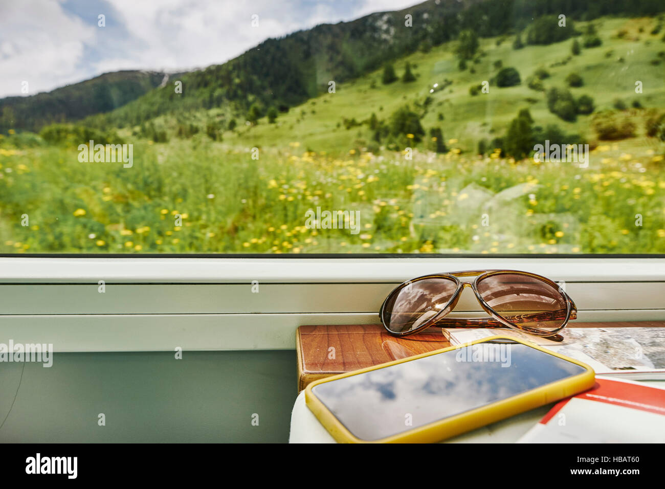 Sunglasses and smartphone by passenger train window, Chur, Switzerland Stock Photo