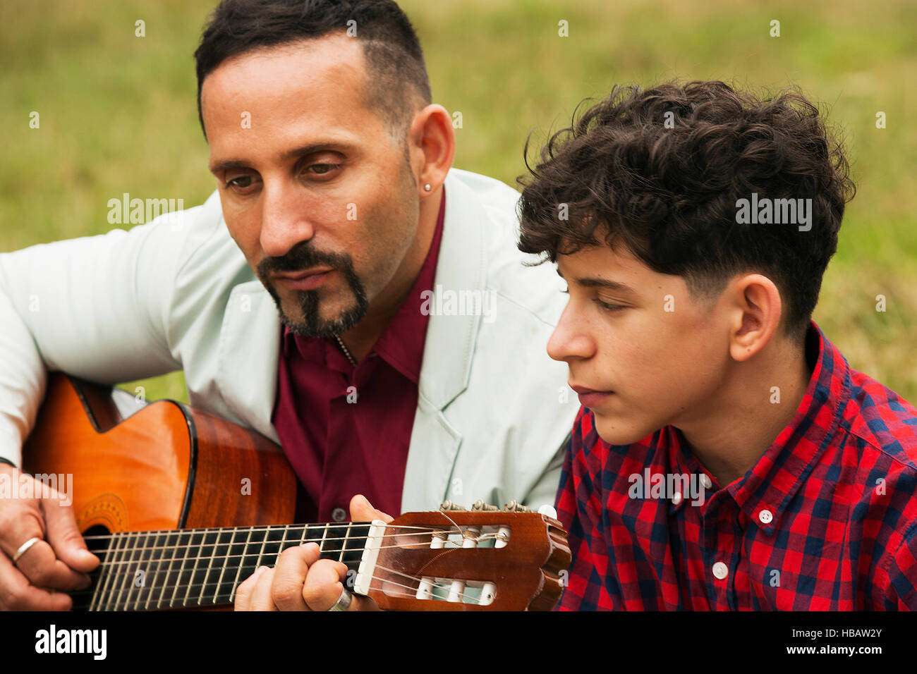 Father and son outdoors, father playing guitar Stock Photo