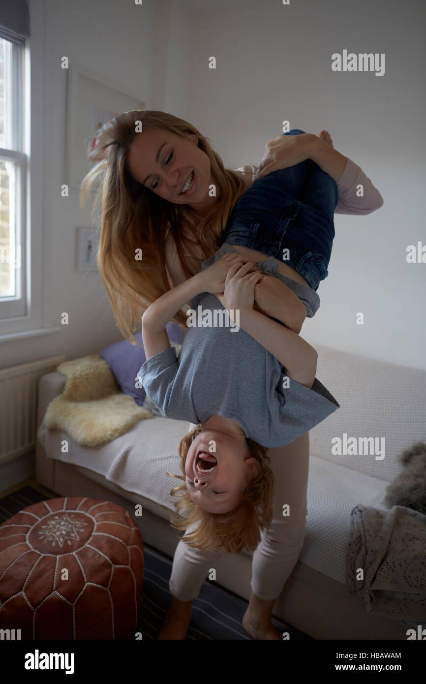 Mid adult woman holding son upside down in living room Stock Photo
