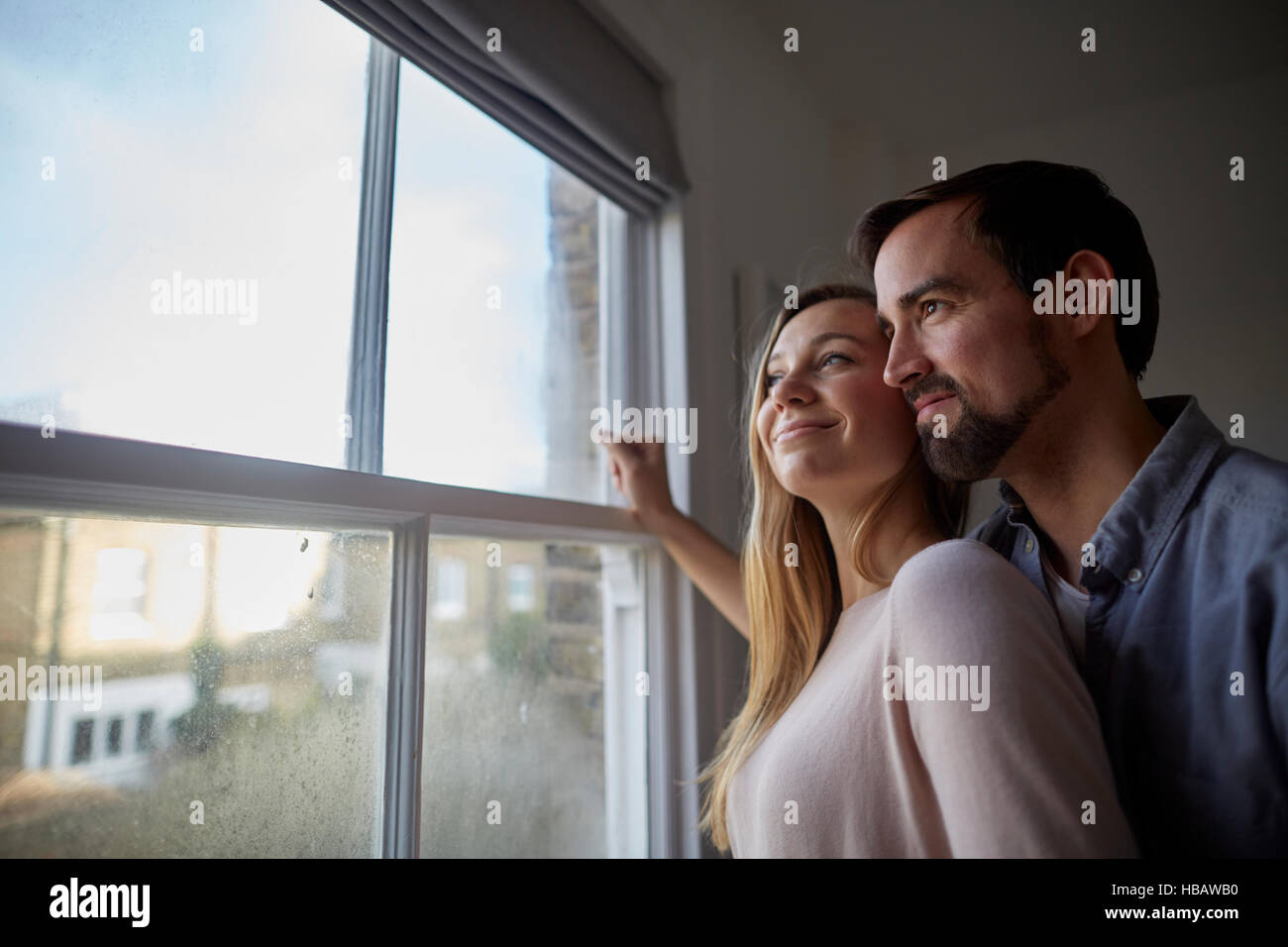 Mid adult couple looking out through bedroom window Stock Photo
