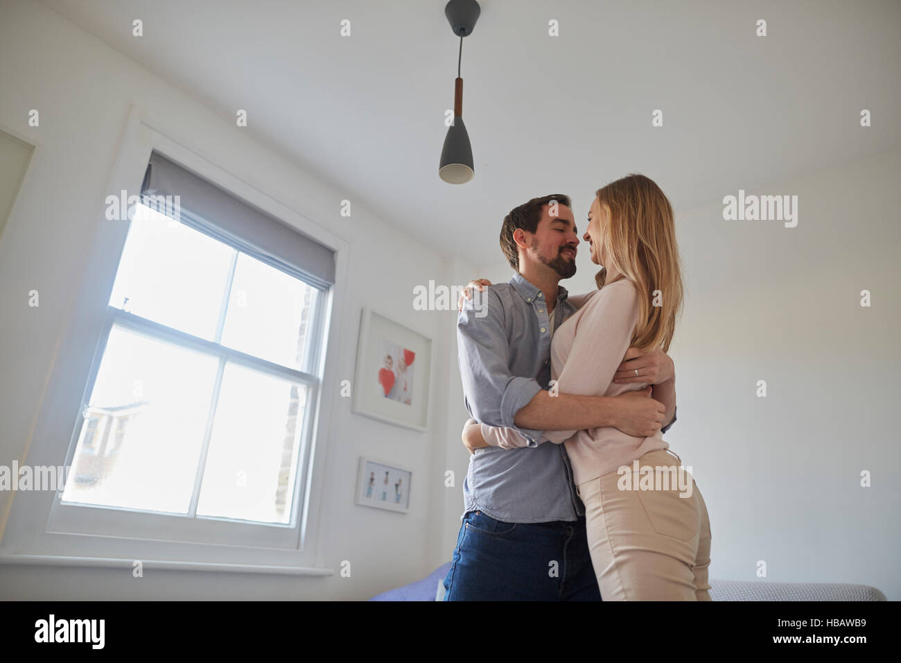 Mid adult couple hugging in living room Stock Photo