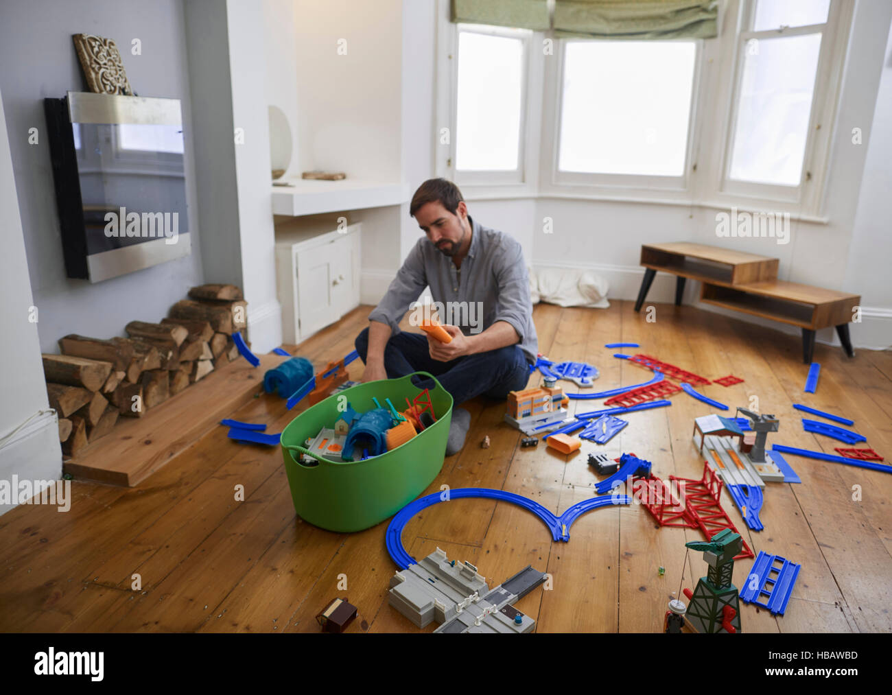 Mid adult man contemplating toys scattered in living room Stock Photo