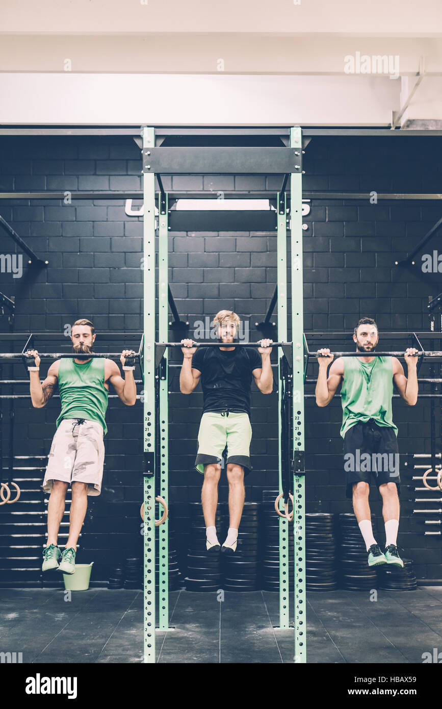 Two male cross trainers doing chin ups on exercise bar in gym Stock Photo