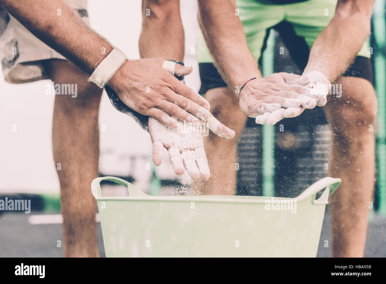 Cropped shot of two male cross trainers chalking hands in gym Stock