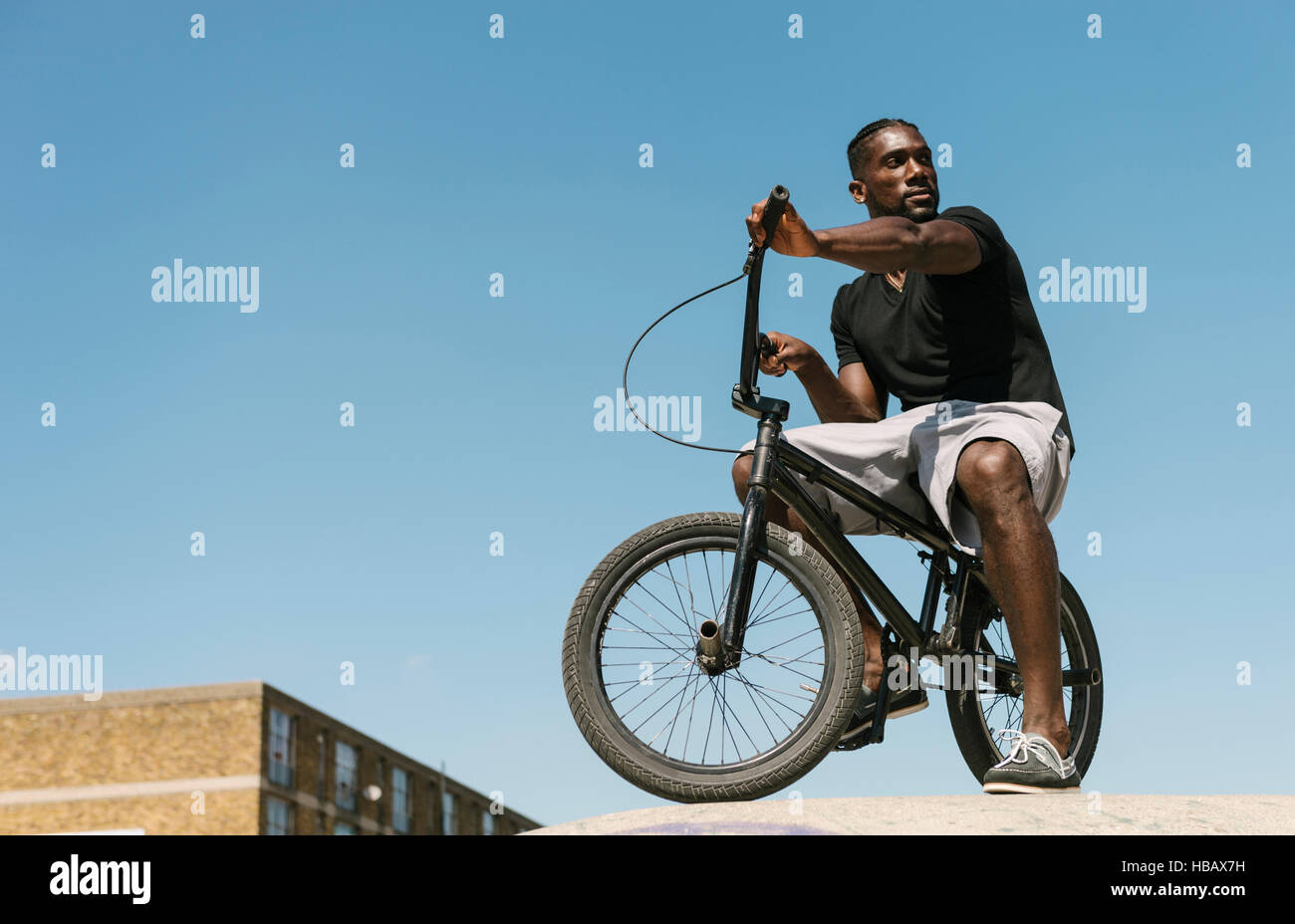 Young man on BMX bicycle looking over his shoulder in skatepark Stock Photo