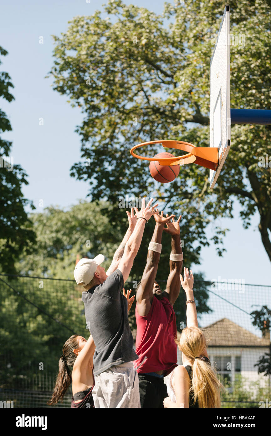 Female and male basketball players throwing ball at basketball hoop Stock Photo