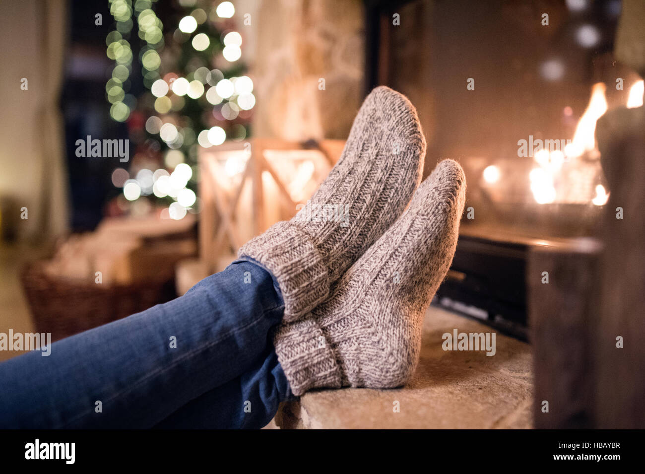 Feet of unrecognizable woman in socks by the Christmas fireplace Stock Photo