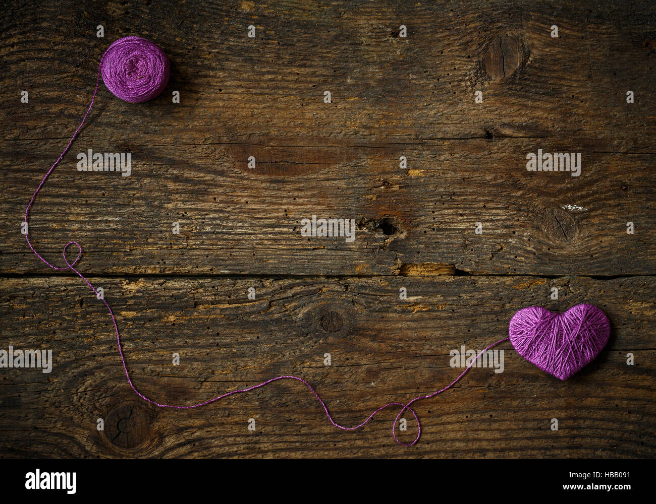 Purple Heart with a ball of thread on on old shabby wooden background ...