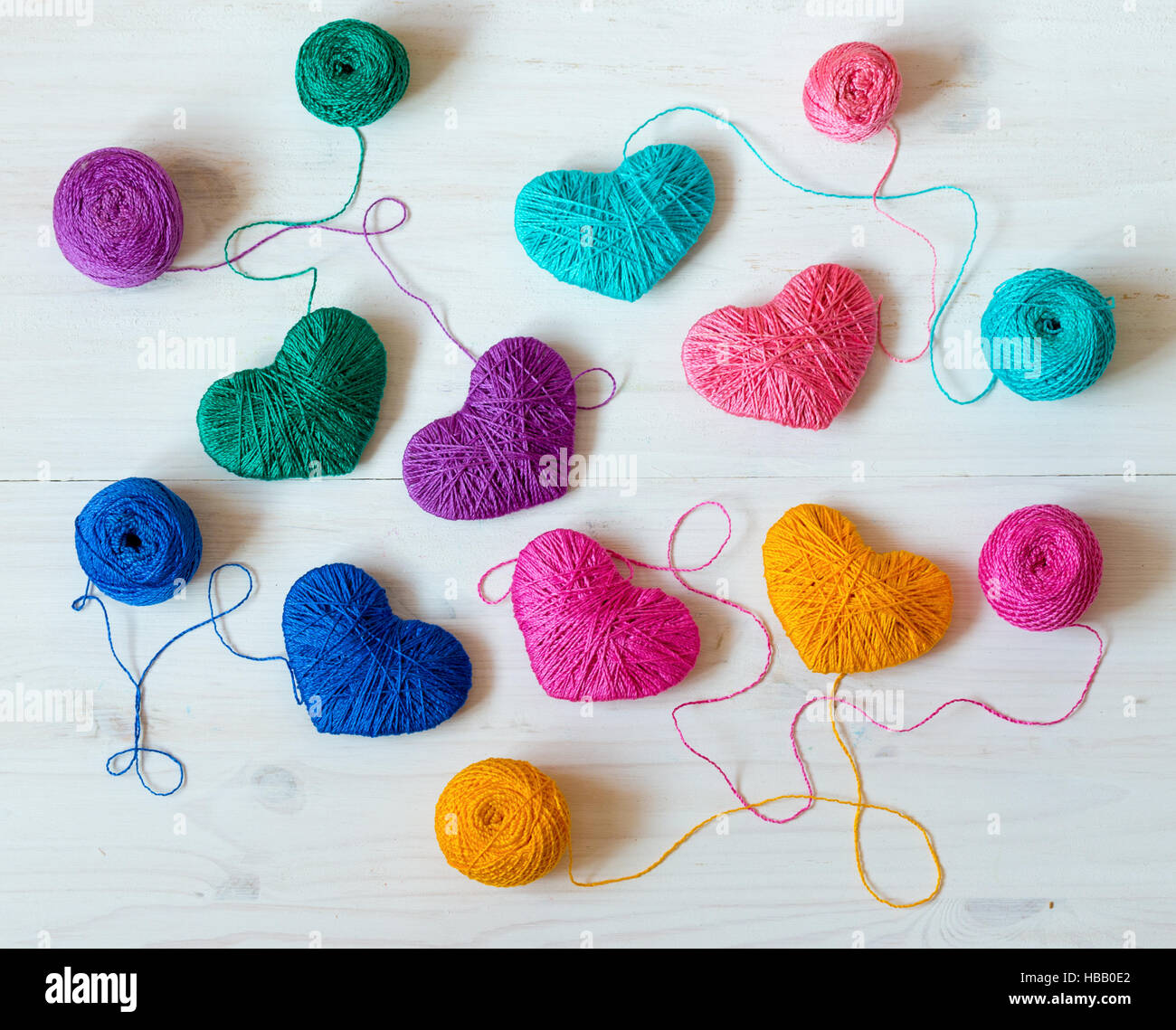 Multicolored Hearts with a balls of thread on white wooden background ...