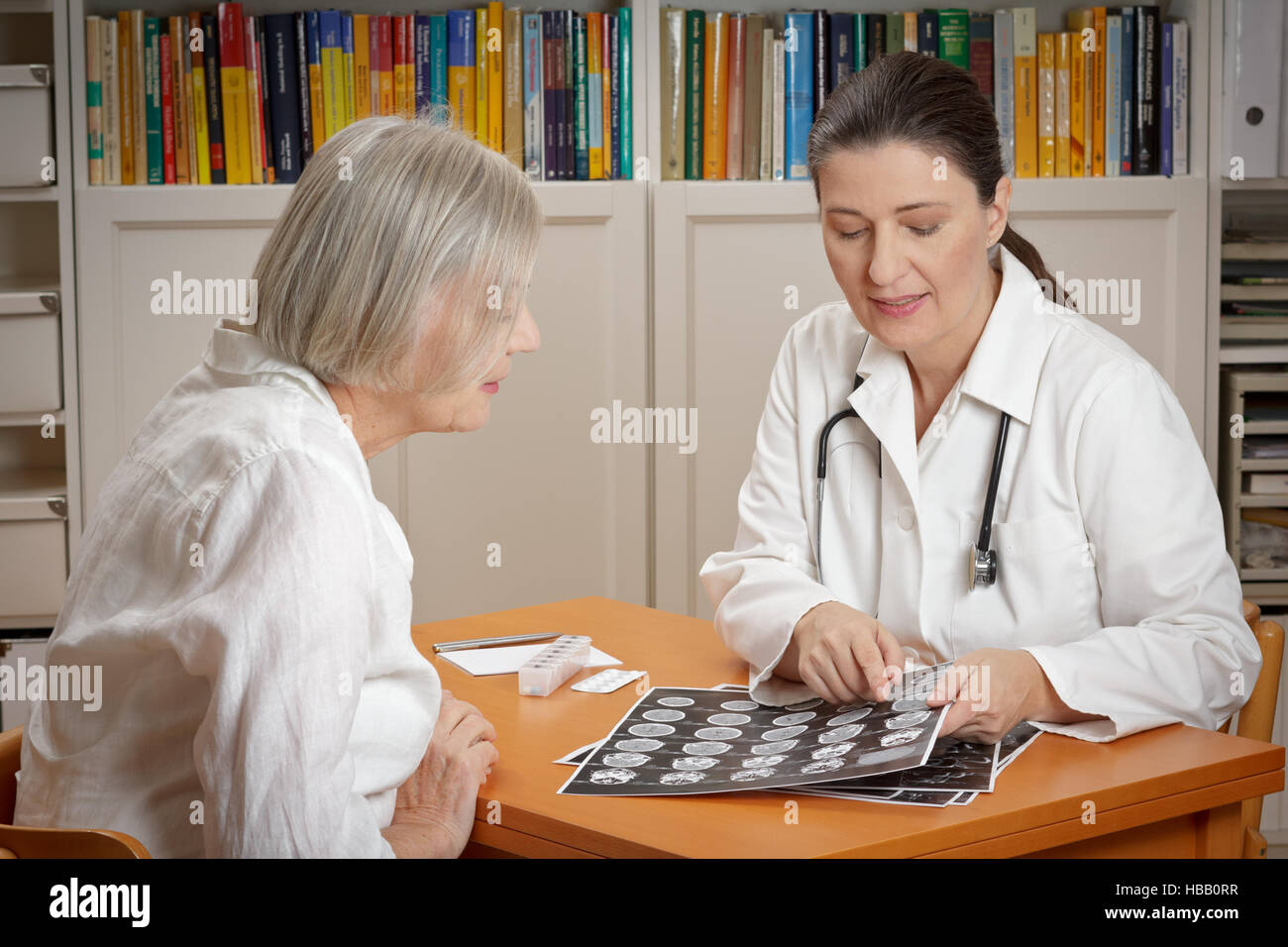 Two women in a hospital office: doctor showing her senior patient a printed sheet of computer tomography images of her brain Stock Photo