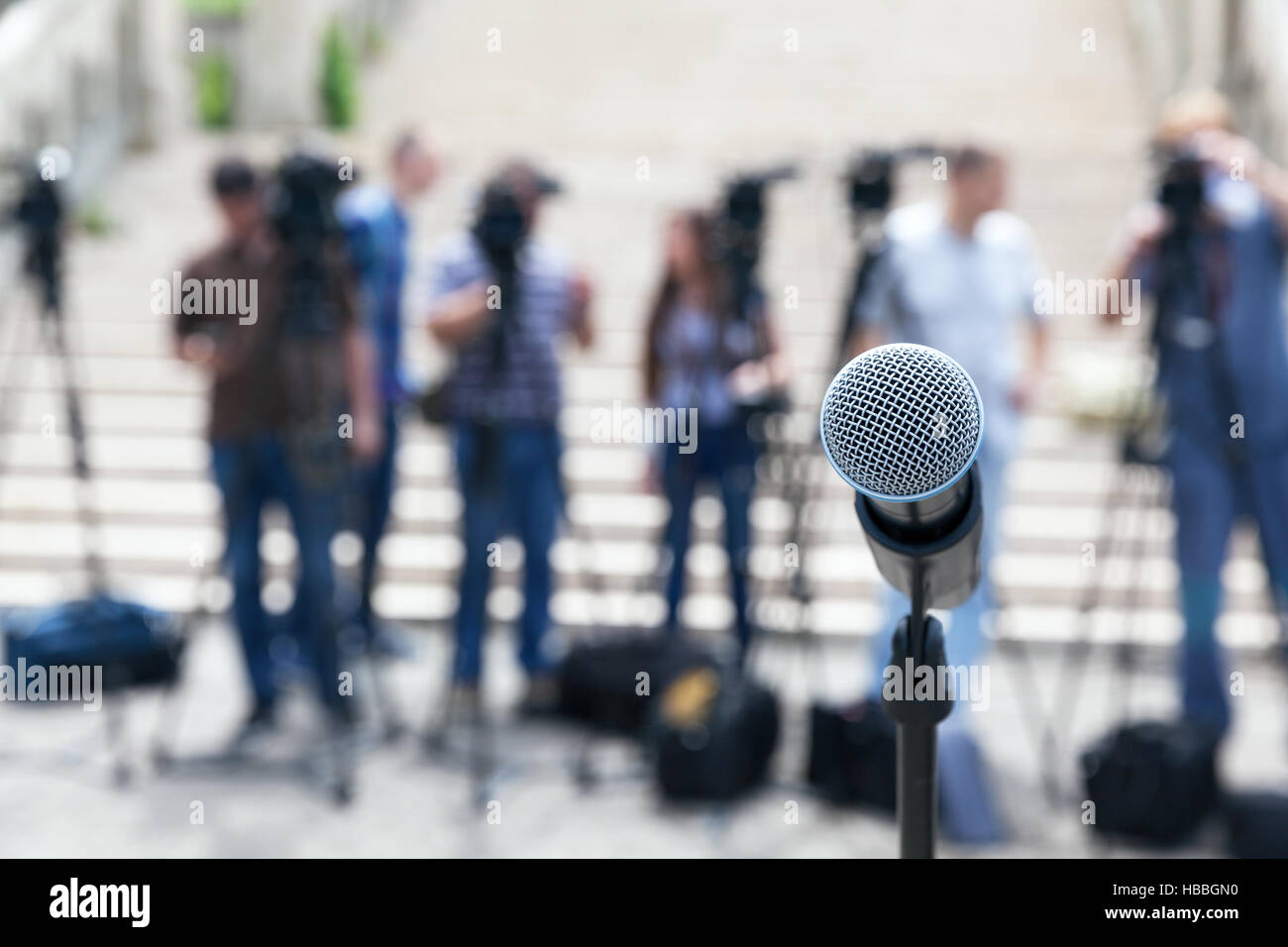 Microphone in focus against blurred camera operators and journalists. Press conference. Stock Photo