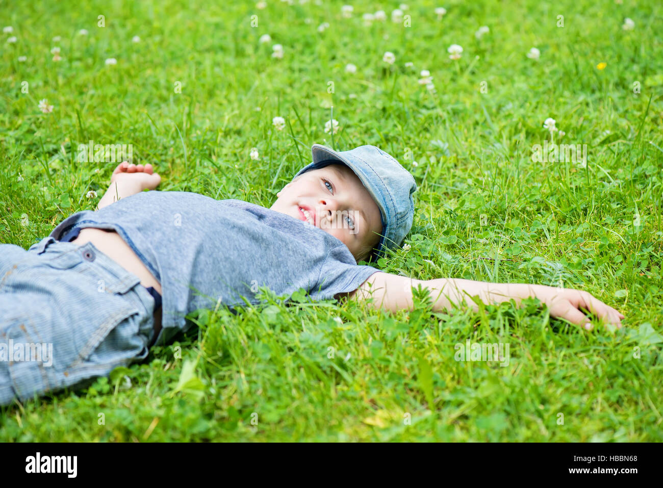 Little caucasian boy resting on grass Stock Photo