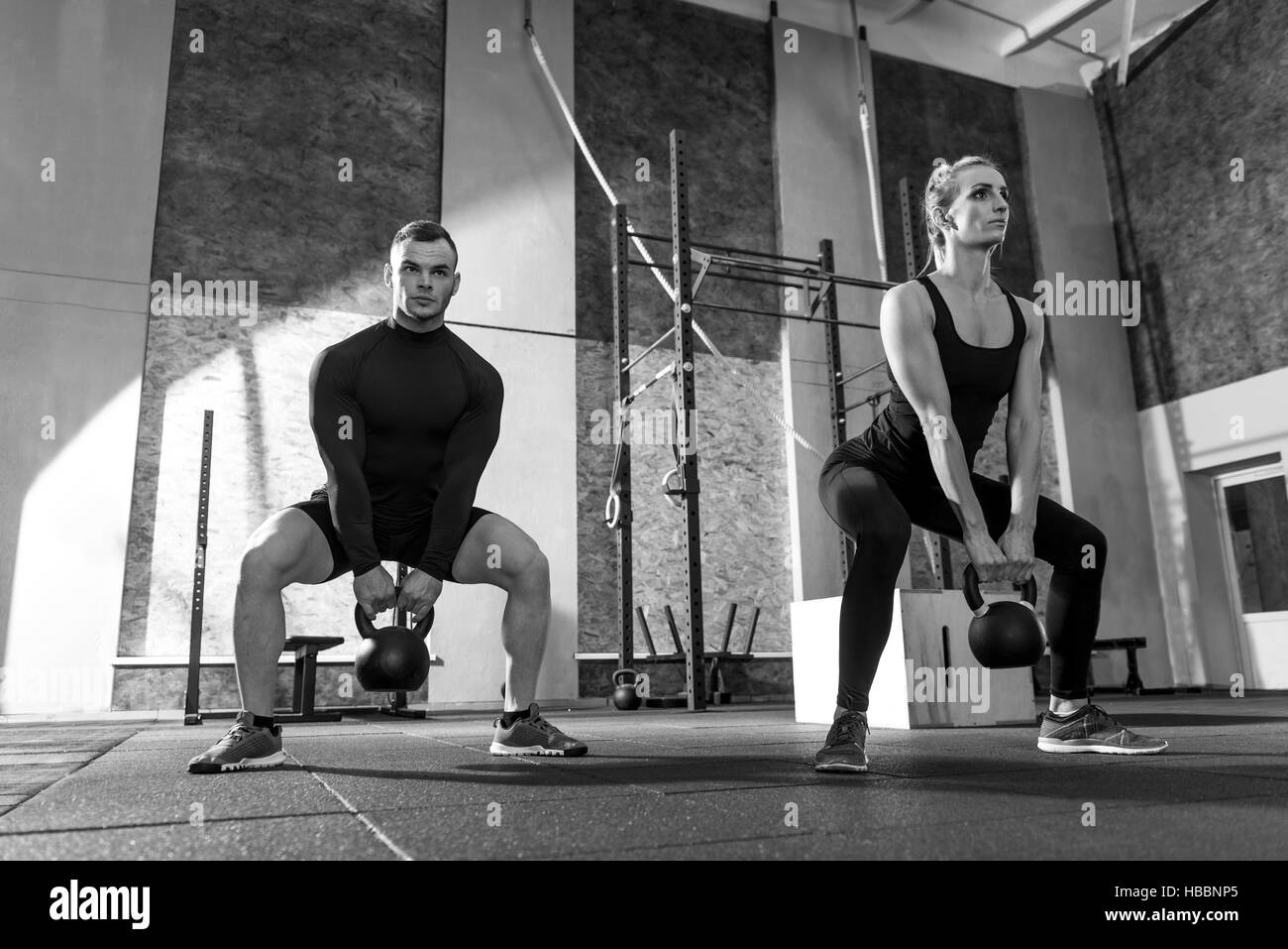 Strong well built man and woman holding kettlebells Stock Photo Alamy