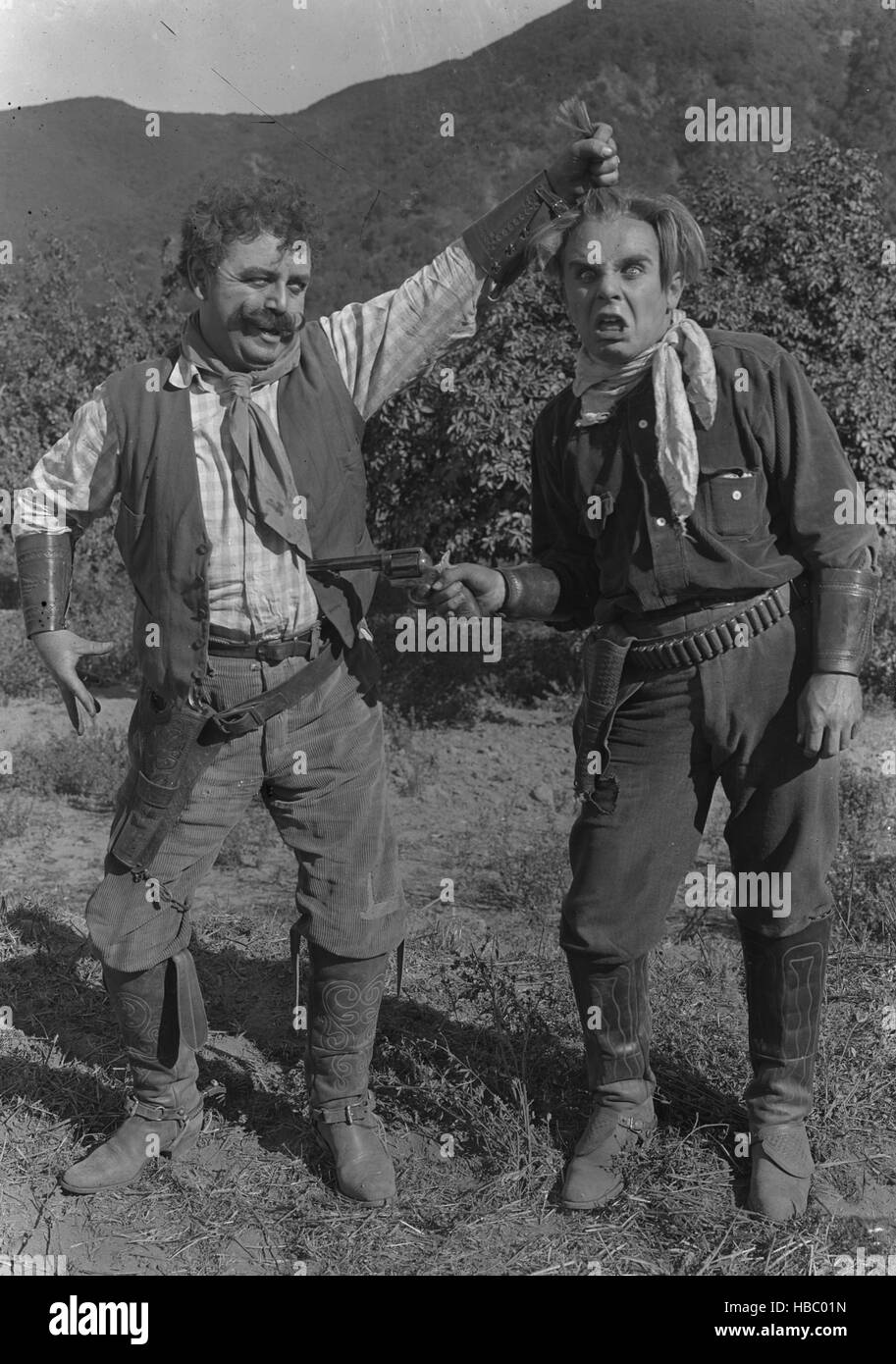 1910s TWO GOOFY COWBOYS ONE POINTING GUN AT BELLY OF THE OTHER PULLING HIS HAIR SILENT MOVIE STILL - 01/01/1910 - Photo by: Stock Photo