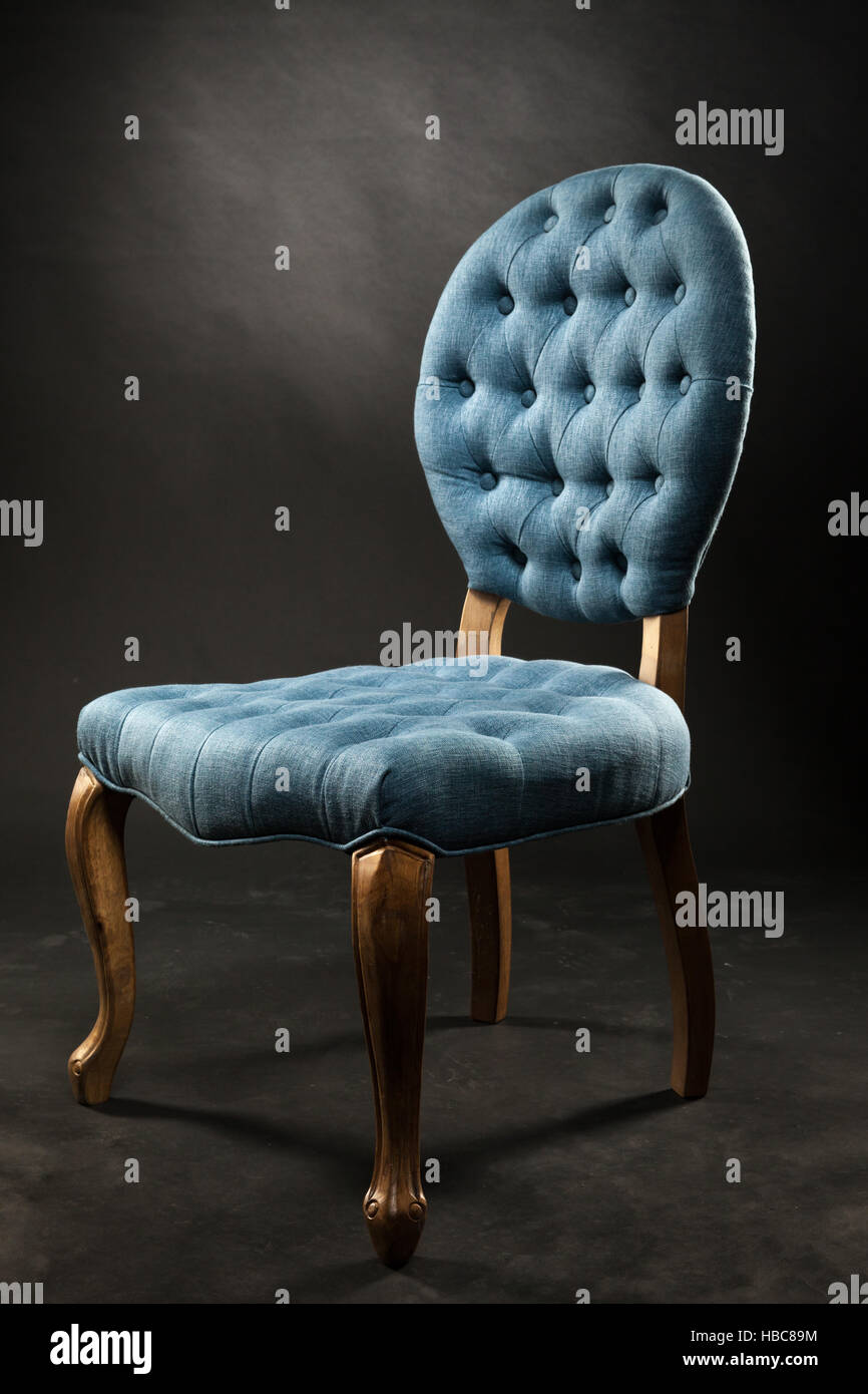 Antique blue velvet chair near a dark room Stock Photo