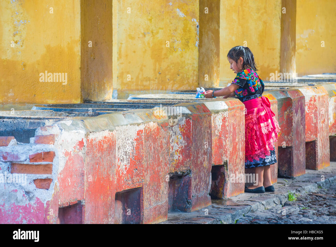 ANTIGUA , GUATEMALA - JULY 30 : Guatemalan girl wash laundry in a traditional street washing facility in Antigua, Guatemala on July 30 2015. Stock Photo