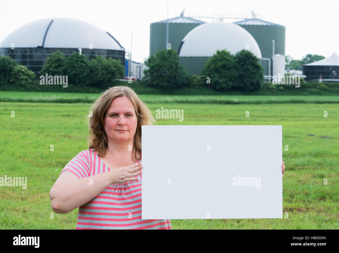 Woman holding a sign in front of a biogas plant Stock Photo