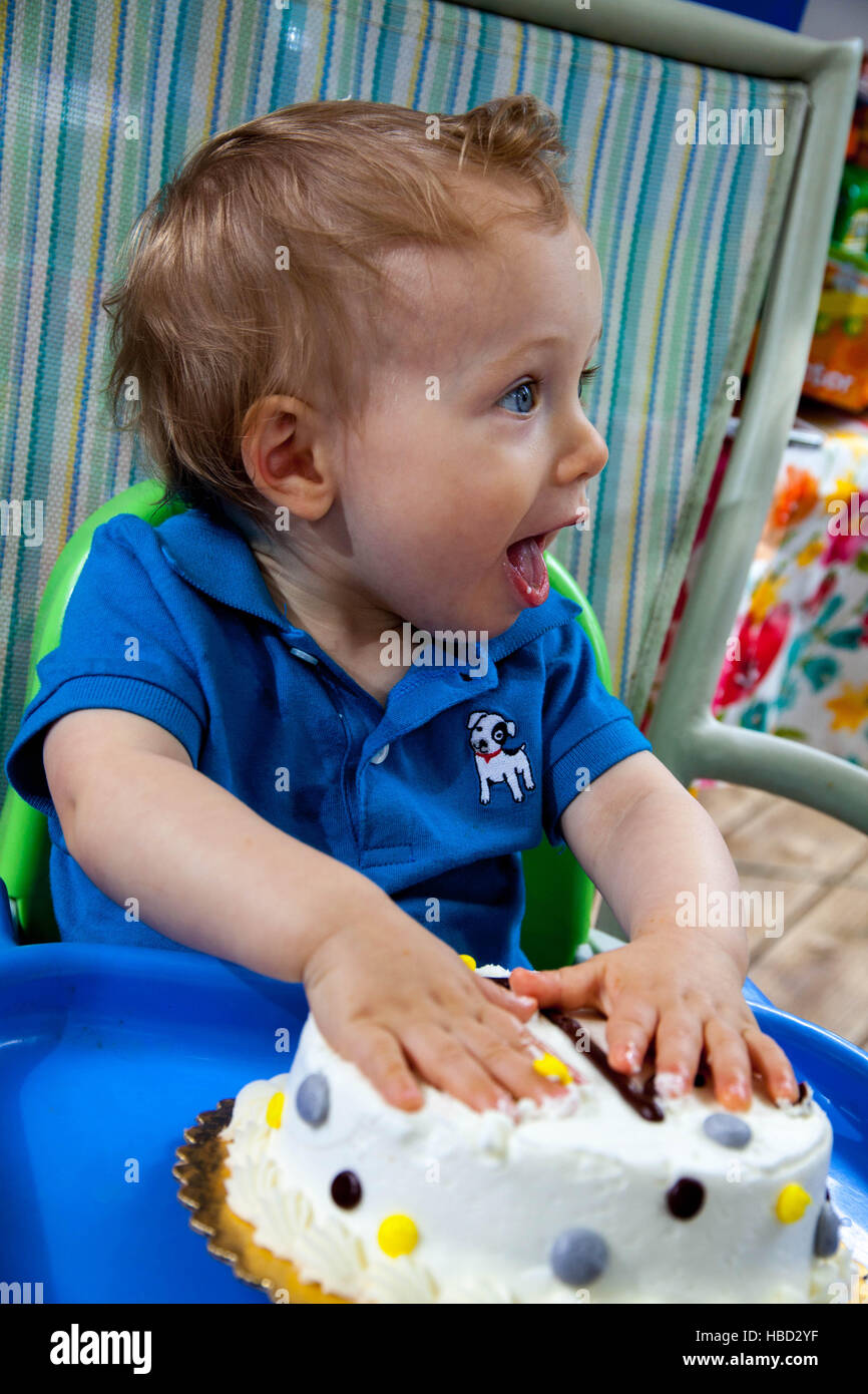 Young Caucasian boy celebrates his first birthday with Cake outside