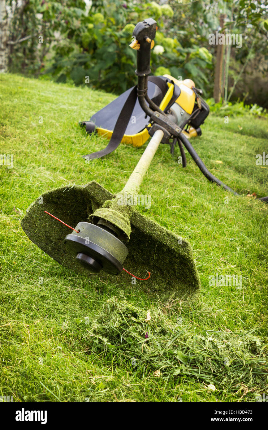 Petrol trimmer on the sloped lawn Stock Photo