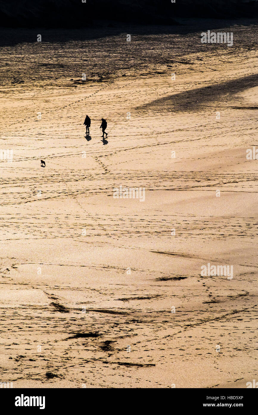 Two people seen in silhouette and from a distance on the award winning Crantock Beach in Newquay, Cornwall. Stock Photo