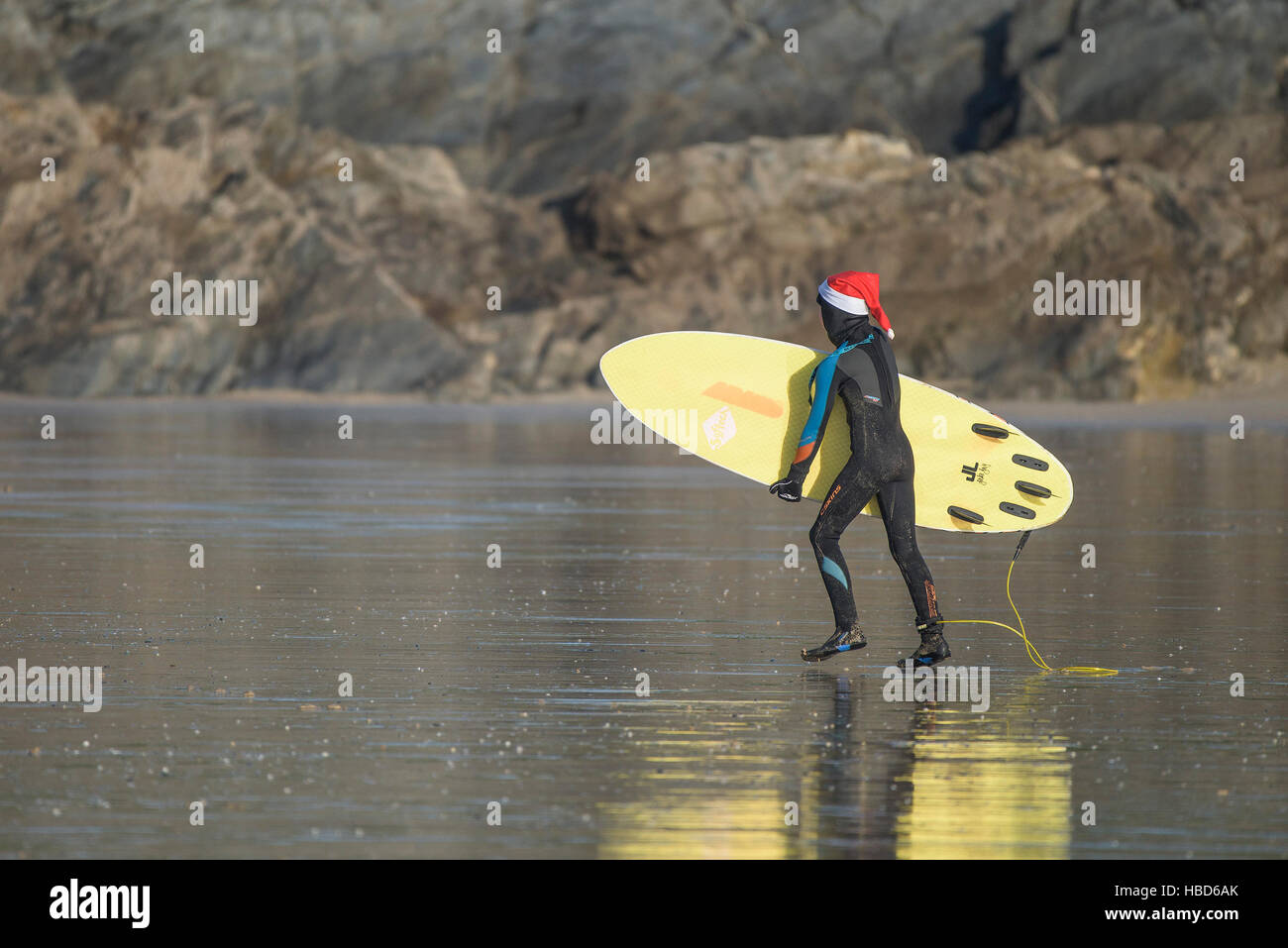 A young surfer wears a Santa hat on a very chilly Fistral Beach in Newquay, Cornwall.   Stock Photo