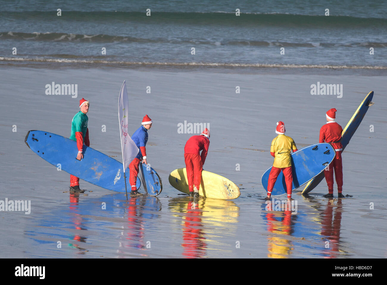 Junior surfing Santas gather at the start of the fund-raising Santa Surfing competition on a very chilly Fistral Beach in Newquay, Cornwall. UK. Stock Photo