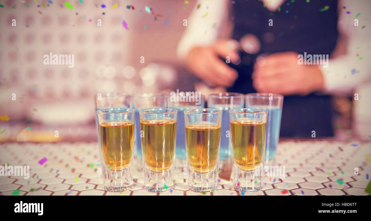 Composite image of glass of blue lagoon drinks and whisky on bar counter Stock Photo