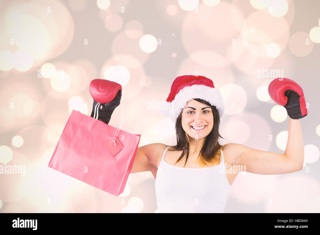 Composite image of festive brunette in boxing gloves holding shopping bags Stock Photo