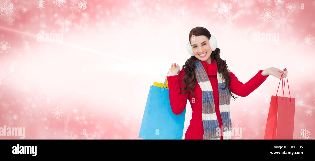Composite image of brunette in winter clothes holding shopping bags Stock Photo