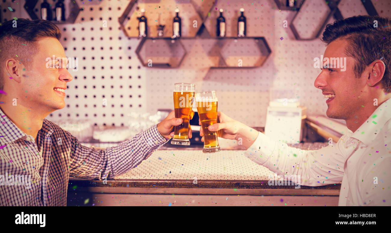 Composite image of two men toasting a glass of beer Stock Photo