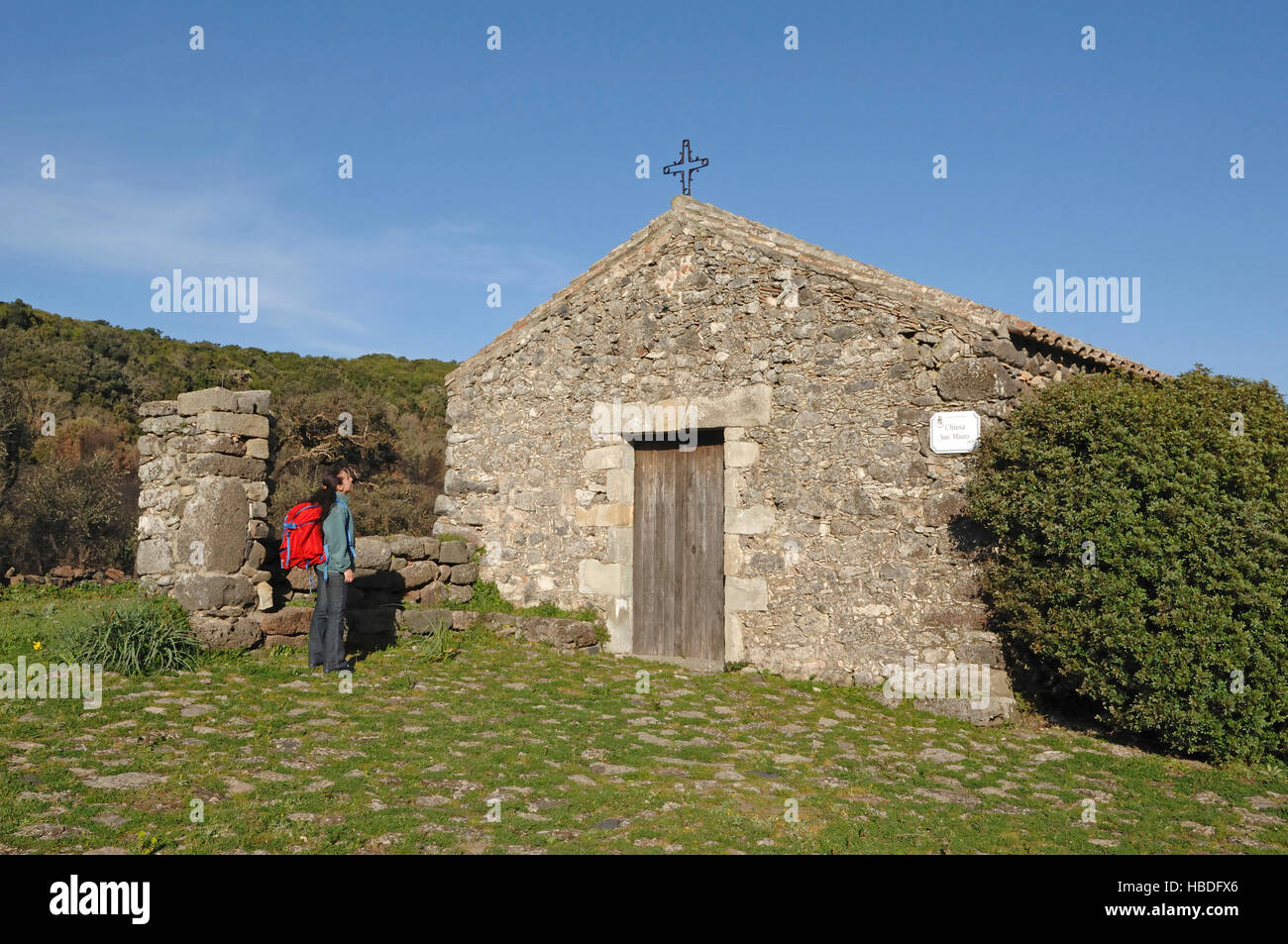 hiker looks the old rural church of San Mauro, Villaverde, Sardinia, Italy Stock Photo