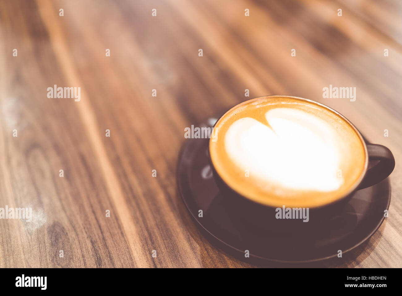 Cup of hot cappuccino coffee with heart shaped latte art whipped cream in vintage tone, copy space on wooden table, love or relax concept Stock Photo
