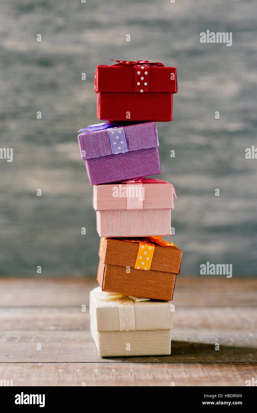 a stack of some cozy gifts wrapped in different papers and tied with ribbons of different colors on a rustic wooden surface Stock Photo