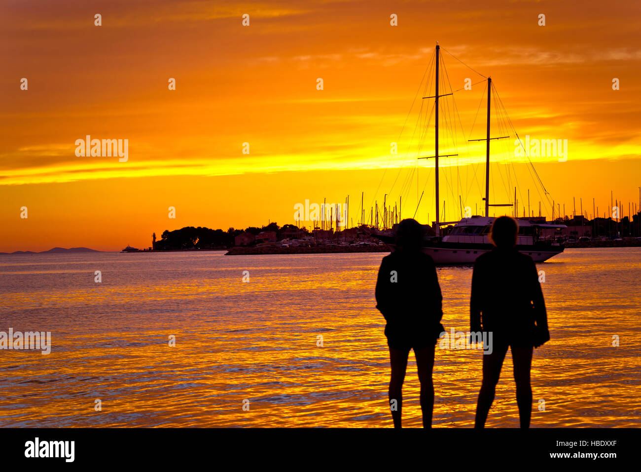 People silhouettes at golden sunset at sea Stock Photo