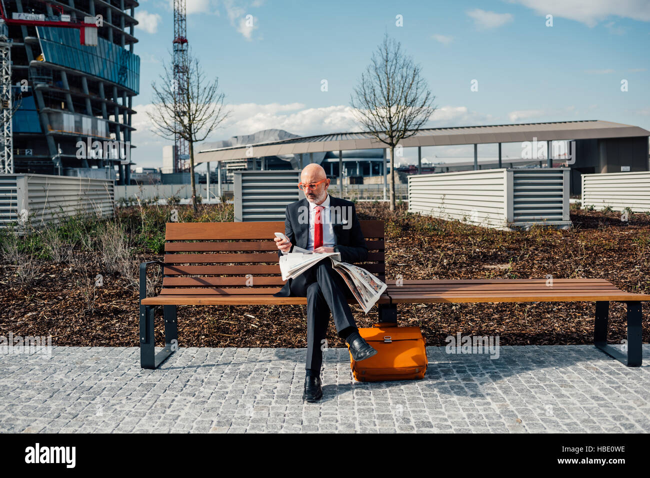 Middle-aged contemporary businessman sitting on a bench outdoor in the ...
