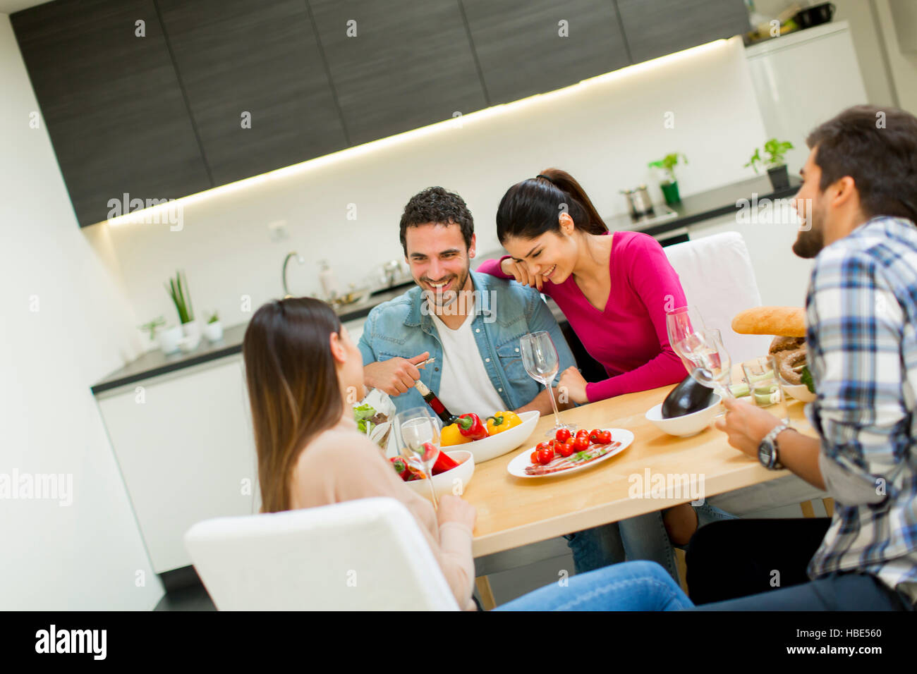 Group of happy young people sitting by the table eating and drinking red wine Stock Photo Alamy