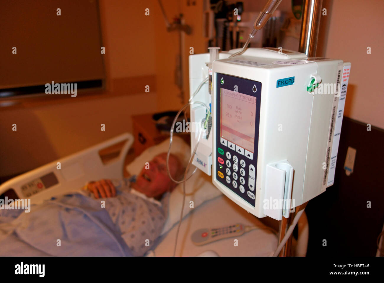 An elderly man lying in a hospital bed being administered drugs by an IV machine Stock Photo