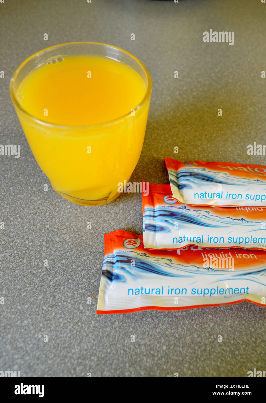 Sachets of natural liquid iron supplements and a glass of Orange Juice  Stock Photo - Alamy