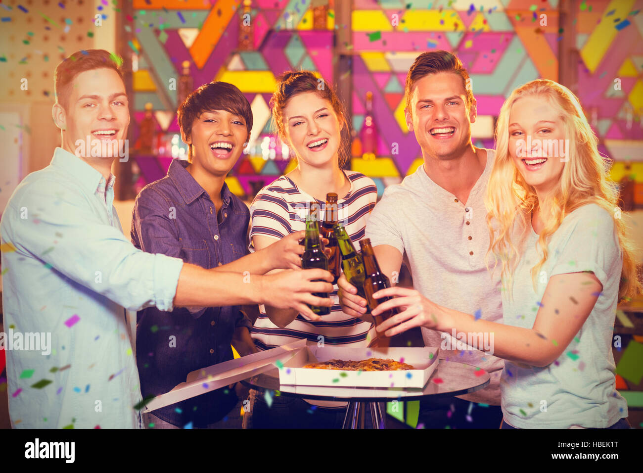 Composite image of group of friends toasting bottle of beer Stock Photo