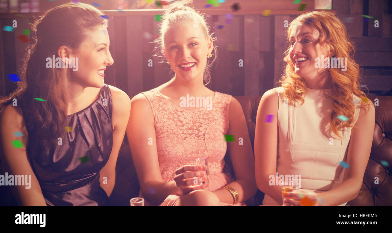 Composite image of three female friends holding shot glass of tequila in bar Stock Photo