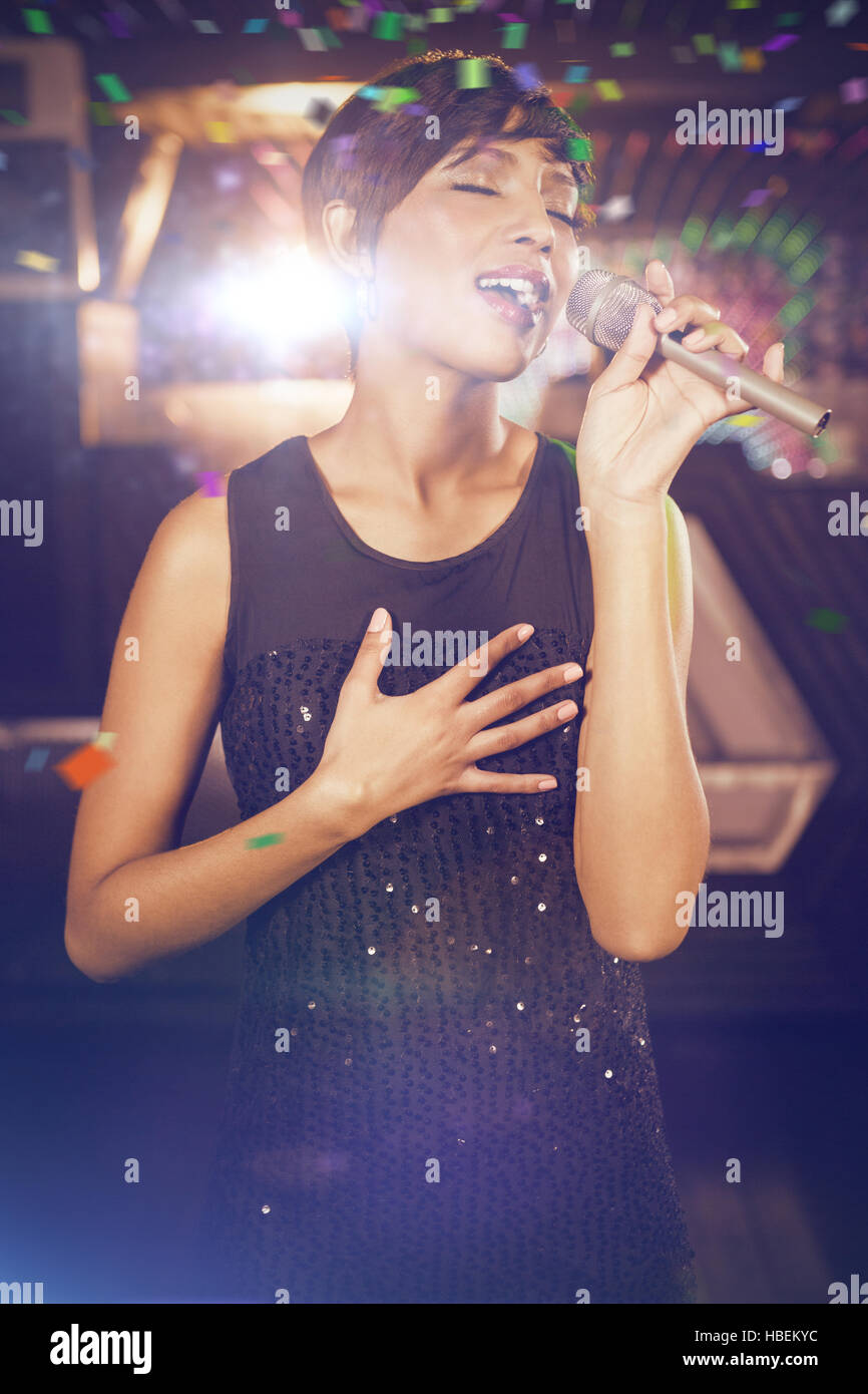 Composite image of woman singing in bar Stock Photo