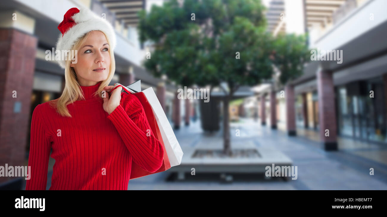 Composite image of happy festive blonde with shopping bags Stock Photo