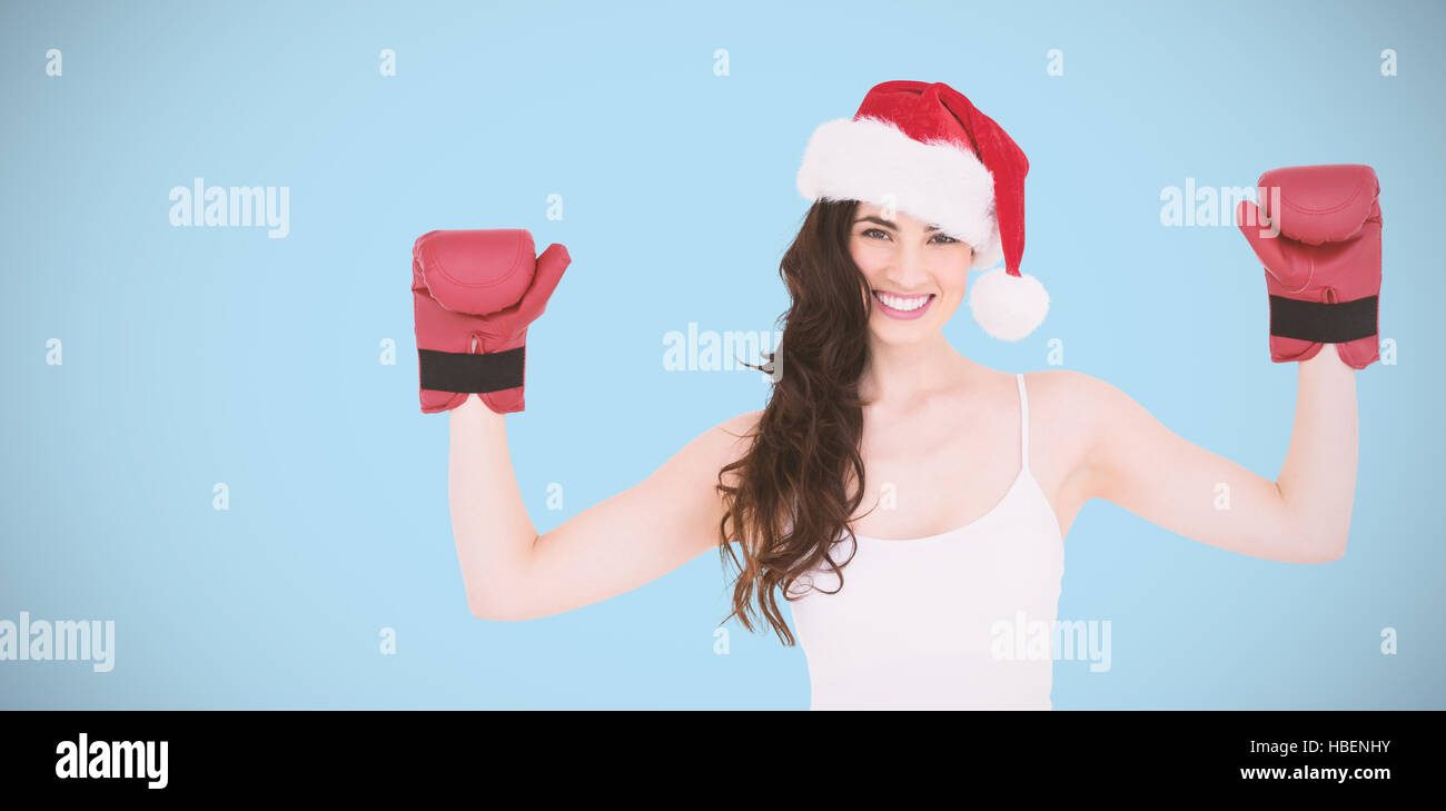 Composite image of festive brunette in boxing gloves with arms raised Stock Photo