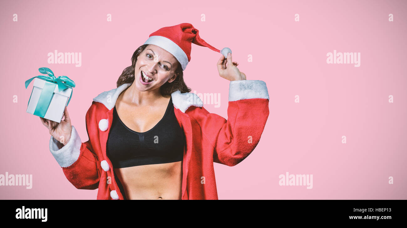 Composite image of portrait of female athlete in christmas costume and holding gift Stock Photo
